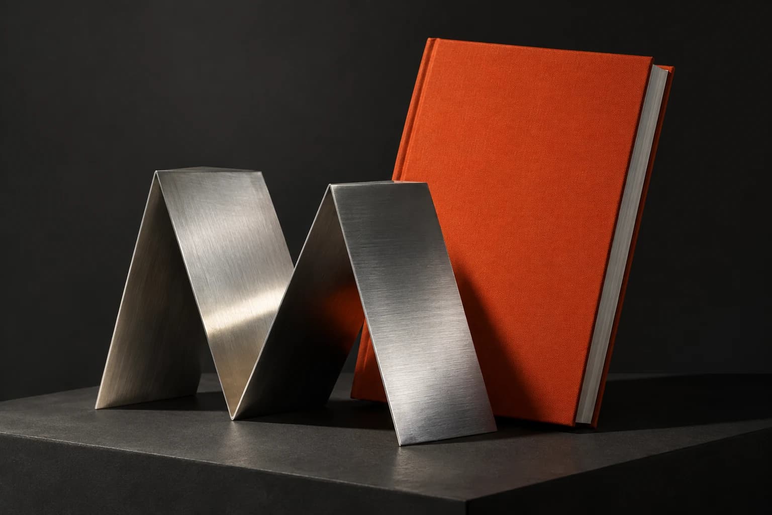 Fırçalanmış metal M formu ve turuncu katalog: sanayi ile tasarımın buluşması